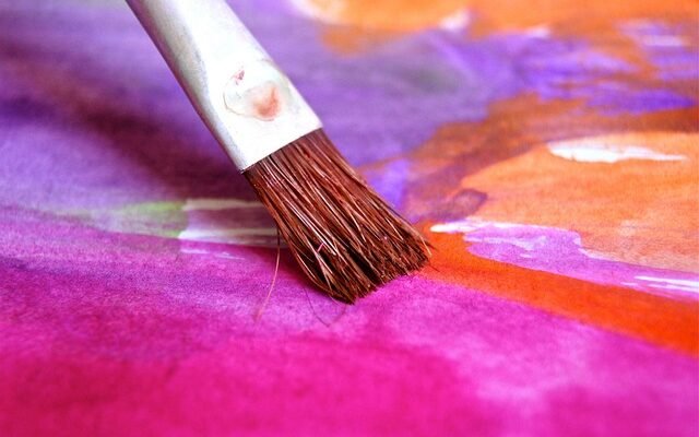 A brush is actively painting on a vivid fabric, capturing the essence of artistic expression in textile design.