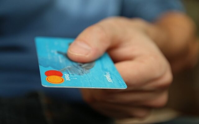 A hand holding a credit card, illustrating financial responsibility and credit score insights from Gomyfinance.com.